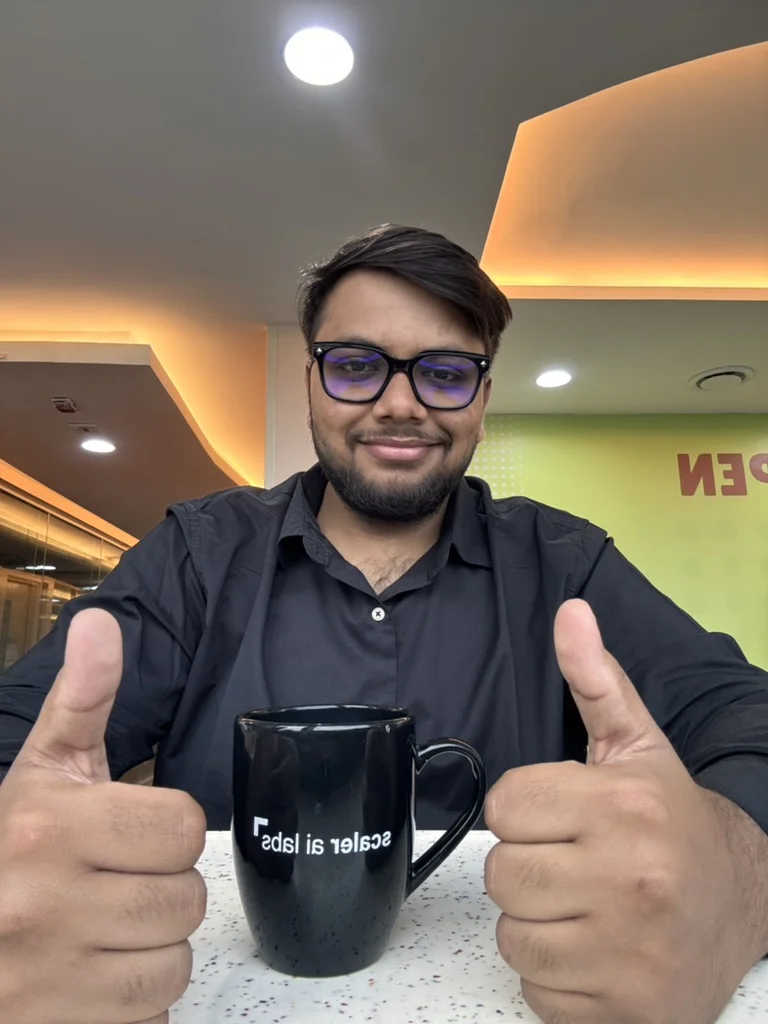 Prakarsh giving two thumbs up behind a Scaler AI Labs mug
